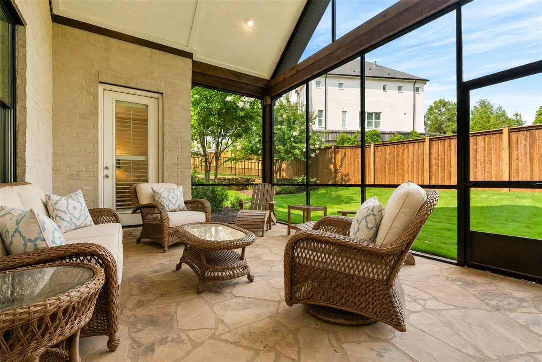 This inviting screened porch serves as a true outdoor living room, combining natural flagstone, soaring ceilings, and tranquil backyard views.