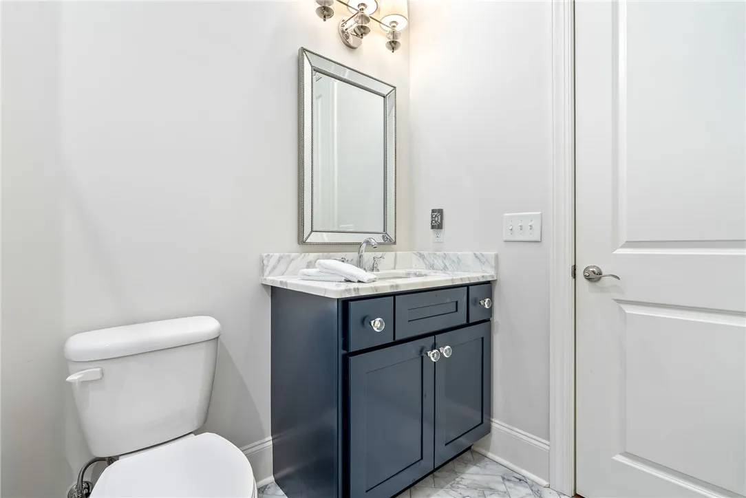 Bath 2 pairs a marble-topped vanity with elegant lighting, classic hardware, and a beautifully framed mirror.