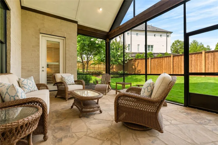 This inviting screened porch serves as a true outdoor living room, combining natural flagstone, soaring ceilings, and tranquil backyard views.