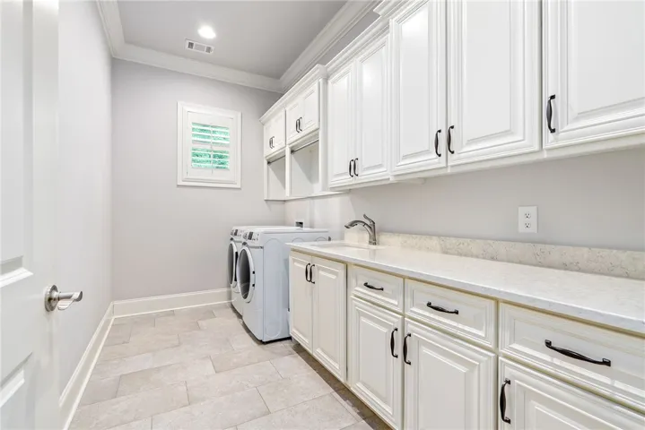 Outfitted with extensive cabinetry, the spacious laundry room offers exceptional storage for household essentials.