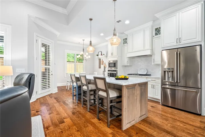 Pendants in the mercury-glass style, a beautiful hood, glass cabinets with trim details, and a unique backsplash contribute to the kitchen's appeal.