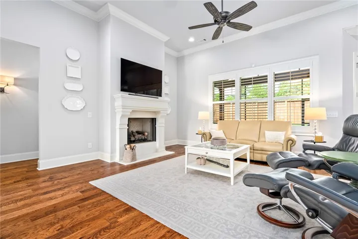 Filled with natural light, the great room features a triple window, gas fireplace, gleaming hardwood floors, and clean architectural lines.