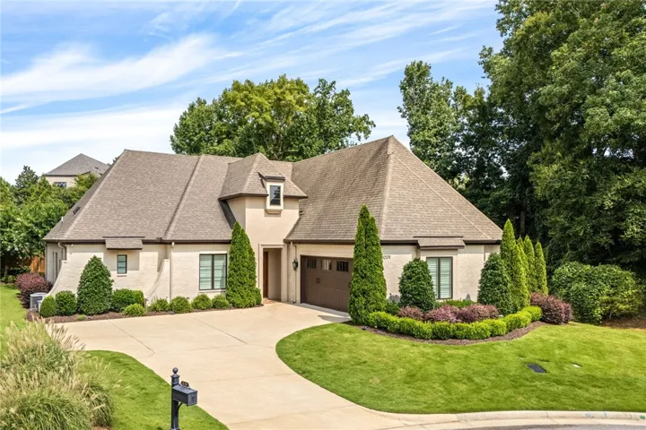 The attractive front elevation features mortar-washed brick, stucco accents, a beautiful wood entry door, and classic wing walls.