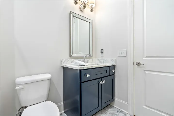 Bath 2 pairs a marble-topped vanity with elegant lighting, classic hardware, and a beautifully framed mirror.