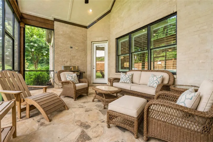 This inviting screened porch serves as a true outdoor living room, combining natural flagstone, soaring ceilings, and tranquil backyard views.