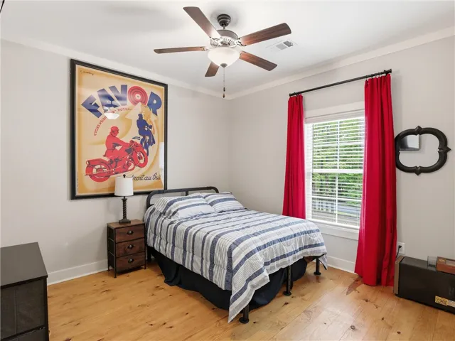 Hardwood floors and a bright window create an inviting atmosphere in this comfortable bedroom.