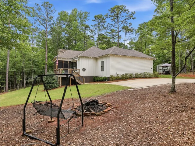 A classic white home featuring a charming screened porch and a welcoming fire pit, perfect for outdoor gatherings.