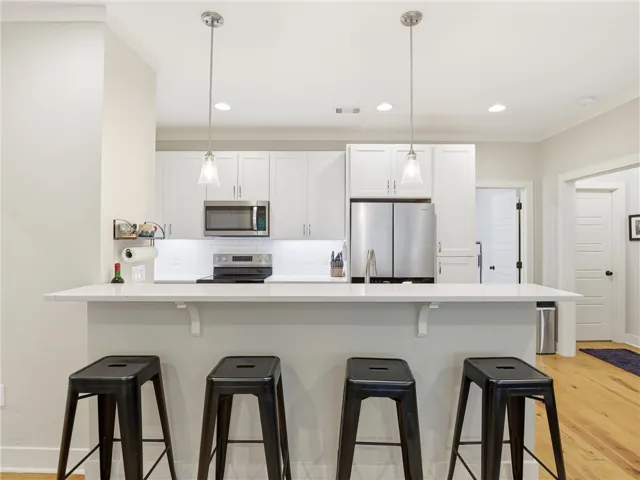 A well-lit kitchen with sleek stainless steel appliances and a comfortable breakfast bar.