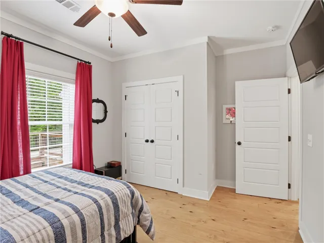 A well-lit bedroom with light wood flooring offers comfortable living space and access to the outdoors.