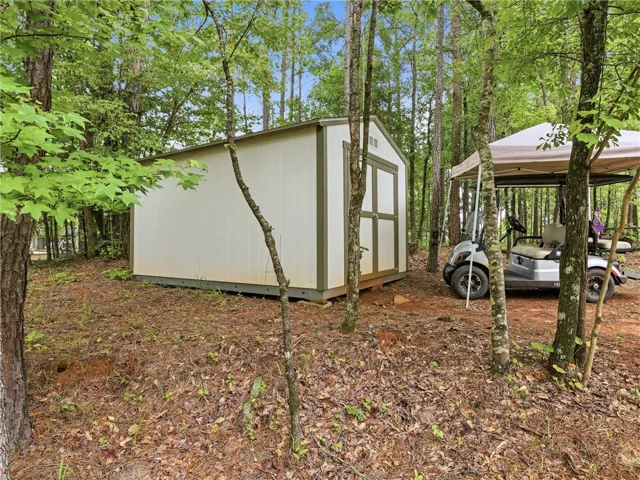 A quaint storage shed nestled amongst verdant trees, offering practical outdoor utility.