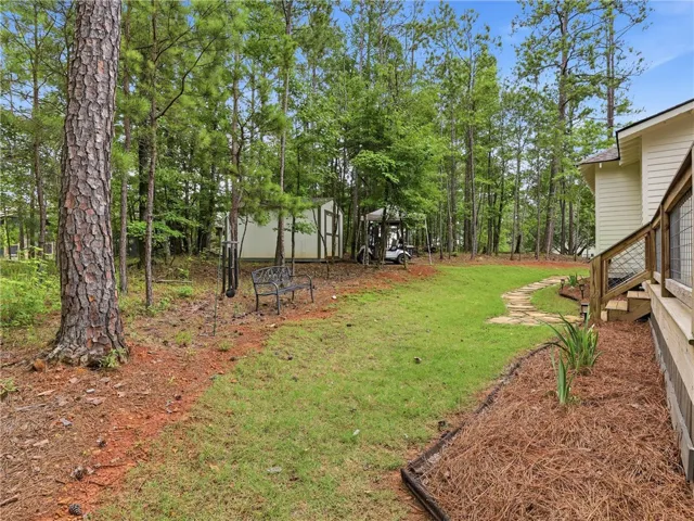 A tranquil backyard offers a stone pathway leading through verdant lawns to a secluded shed.