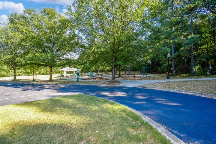 A community park with abundant trees, a walking path, and a recreational area for all ages.