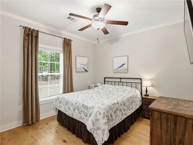 A restful bedroom offers wide plank flooring and a ceiling fan for year-round comfort.