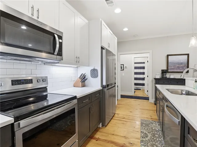 Culinary delights await in this bright kitchen, complete with modern appliances and rich hardwood flooring.