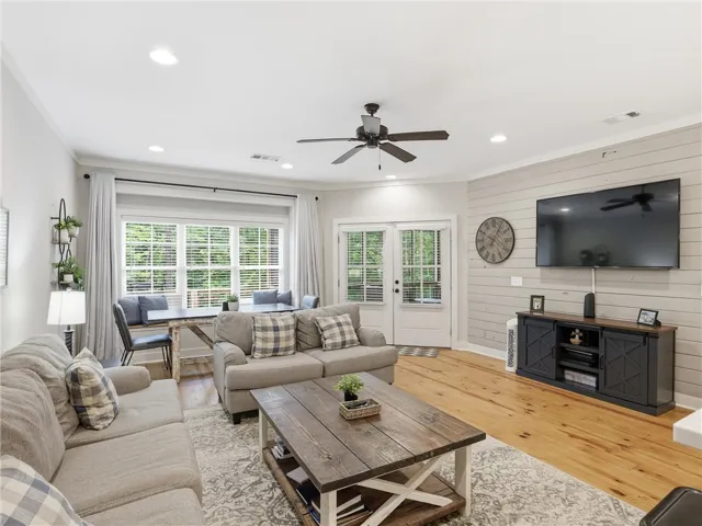 Natural light fills this open-concept living space, showcasing polished wood flooring and access to outdoor recreation.