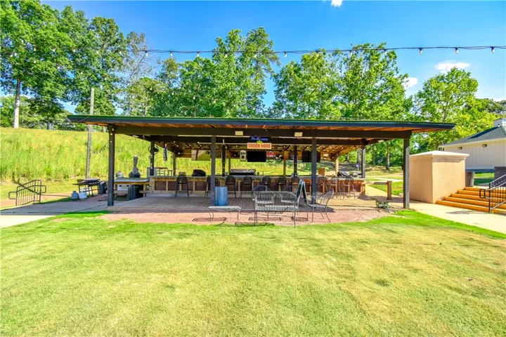 Lush green lawn fronts a covered outdoor bar, ideal for entertaining guests.