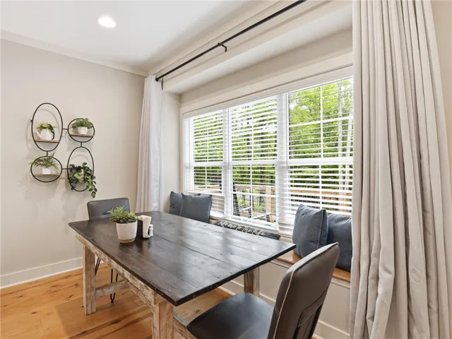 A window-side dining space features rich wood flooring and abundant natural illumination.