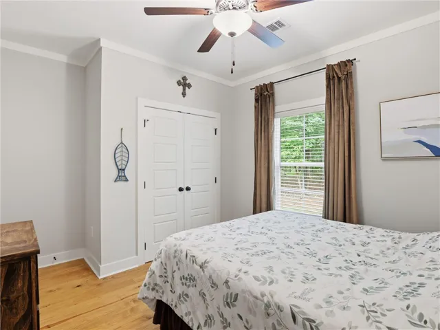 An inviting bedroom features rich hardwood flooring and a functional ceiling fan for comfort.