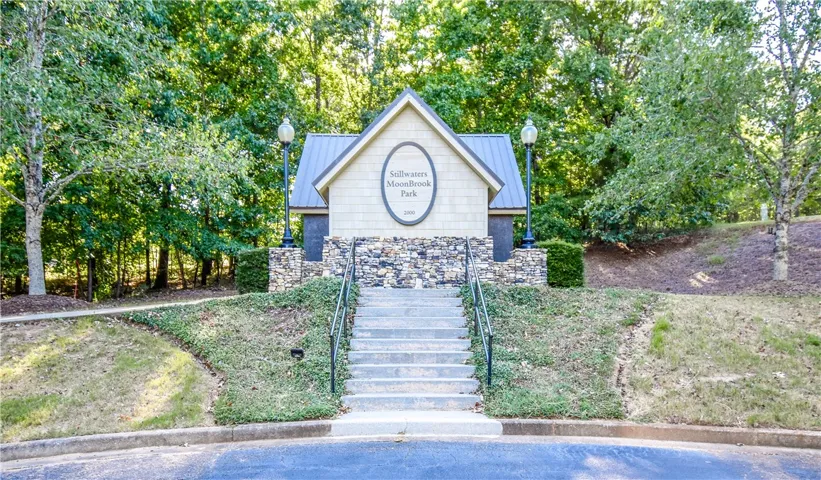 Discover the inviting stone and wood-clad entrance to MoonBrook Park, framed by lush trees and manicured landscaping.
