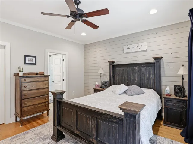 A comforting bedroom with hardwood floors and a ceiling fan awaits.