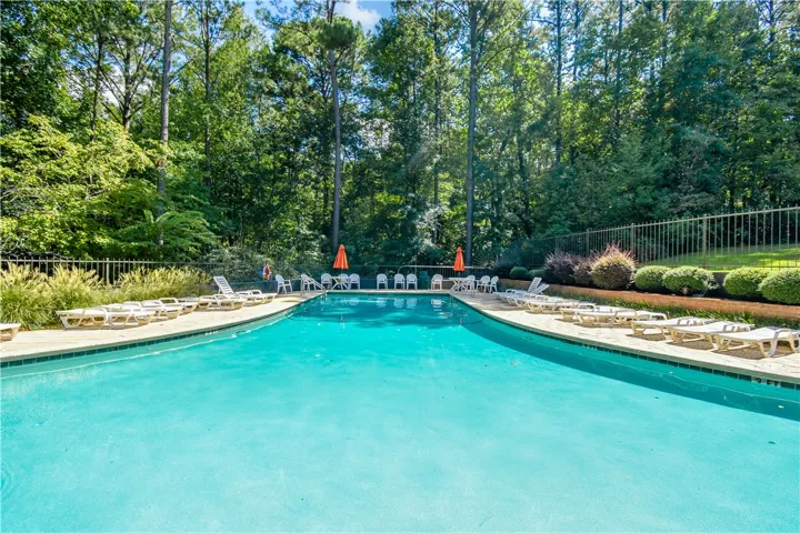 A refreshing outdoor pool, enclosed by lush trees and manicured landscaping, invites relaxation.