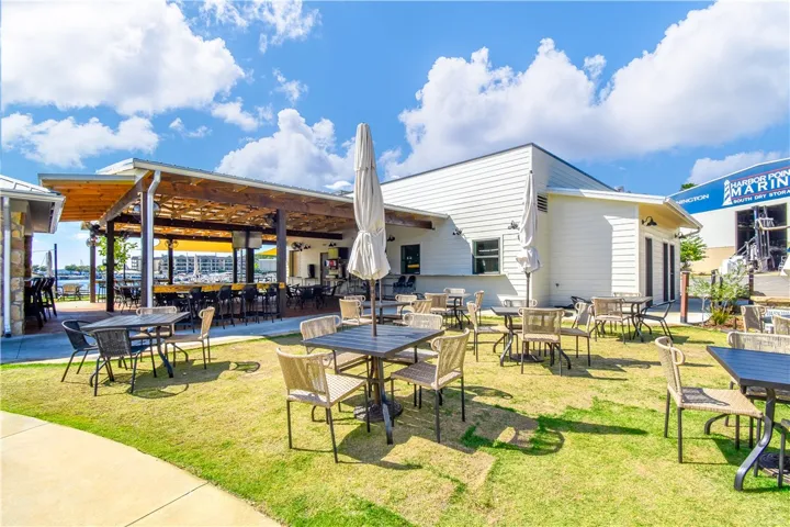 A well-maintained lawn offers ample outdoor dining space beside a waterside establishment.