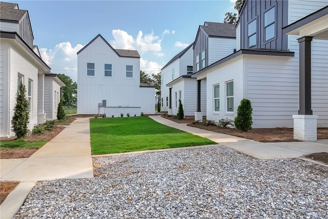 Modern townhomes line a well-maintained lawn with a practical gravel driveway.