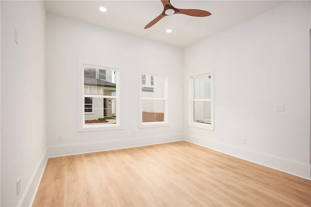 A well-lit bedroom features three large windows and a stylish ceiling fan, creating an inviting retreat.