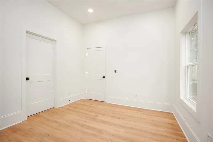 A quiet space with light wood flooring and a recessed light offers versatile living possibilities.
