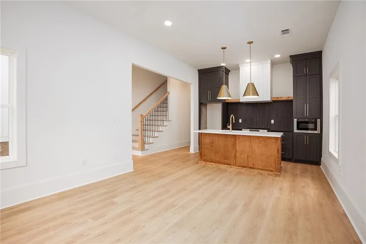 A harmonious blend of modern kitchen amenities and classic staircase architecture creates an inviting open-concept living space.