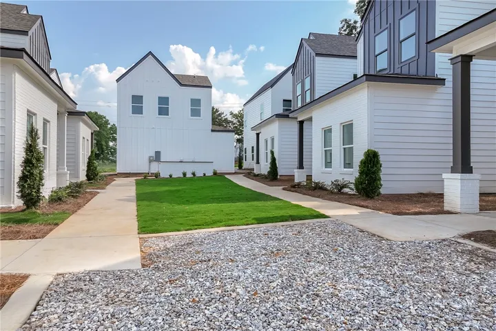 Modern townhomes line a well-maintained lawn with a practical gravel driveway.