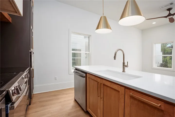 A well-appointed kitchen features warm wooden cabinetry, a sleek white island countertop, and modern lighting fixtures.