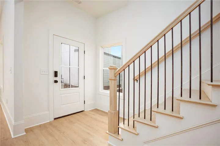 A welcoming entryway with natural light, showcasing durable wood flooring and an elegant staircase.