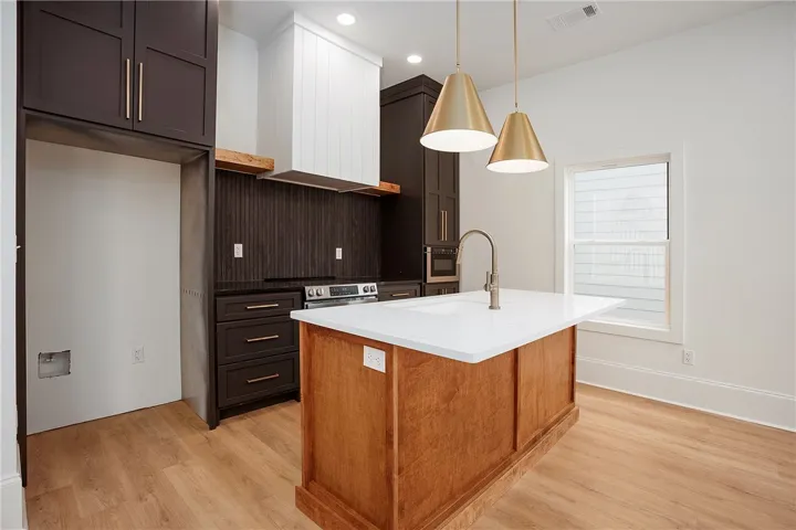 A contemporary kitchen space boasts sleek cabinetry, a substantial island, and modern pendant lighting.