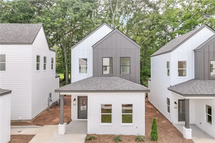 Modern townhome with striking board and batten siding, nestled among mature trees.