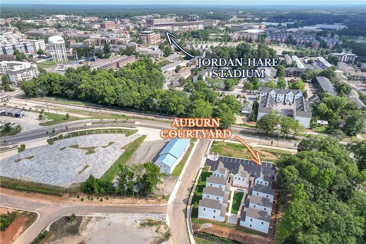 An aerial perspective reveals a modern residential development with ample parking, nestled near a vibrant university campus.