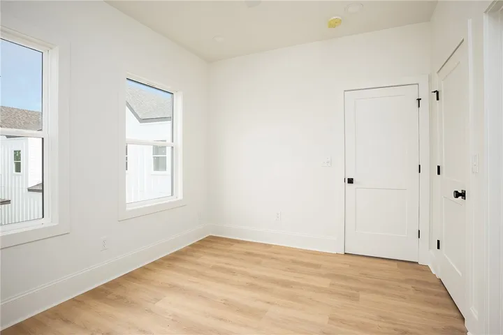 A well-lit bedroom with modern vinyl plank flooring and crisp white walls awaits personalization.