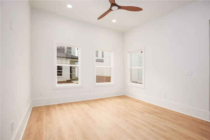 A well-lit bedroom features three large windows and a stylish ceiling fan, creating an inviting retreat.