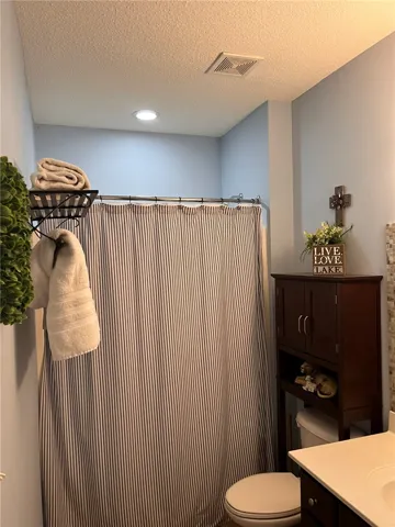 Functional bathroom featuring recessed lighting and a classic striped shower curtain.