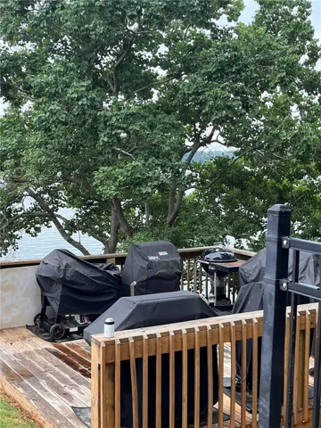 An inviting wood deck overlooks serene water, providing an ideal setting for outdoor cooking and entertaining.