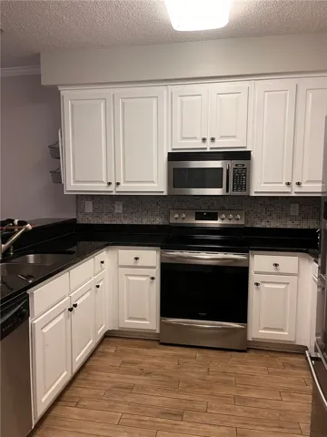 A well-appointed kitchen showcasing contemporary appliances and rich wood-look flooring.