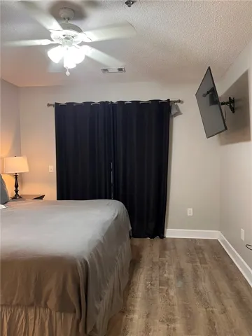 Comfortable bedroom with warm flooring and a ceiling fan, offering a tranquil retreat.