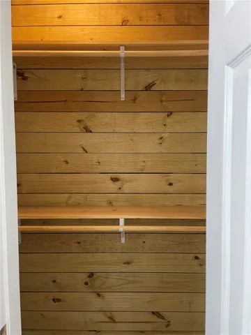 Functional cedar-planked closet with multiple shelving units provides ample storage.