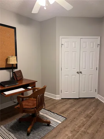 A quiet office space offers productivity with elegant wood flooring and a refreshing ceiling fan.