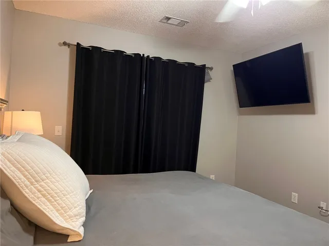 A well-lit bedroom with modern dark curtains and a wall-mounted display provides a comfortable retreat.