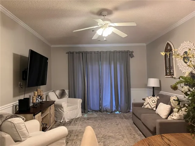 Relax in this well-lit living area featuring crown molding and convenient access to an outdoor space.
