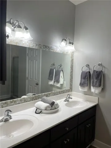 Double vanity with sleek white countertops and ample storage space beneath.