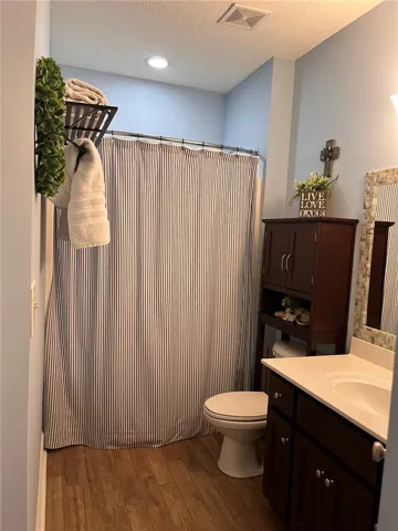 A well-appointed bathroom features wood flooring and a classic striped shower curtain, offering both style and utility.