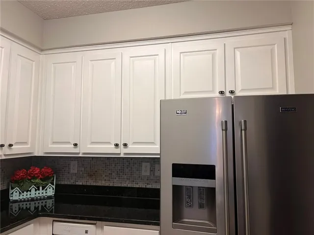 White cabinetry beautifully complements the dark granite countertops in this functional kitchen space.