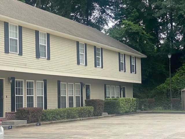 Two-story multi-unit dwelling with neat shrubbery and a convenient paved parking area.